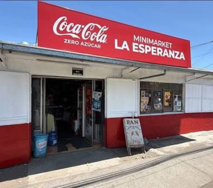 Fachada roja de un minimercado con aviso de Coca-Cola